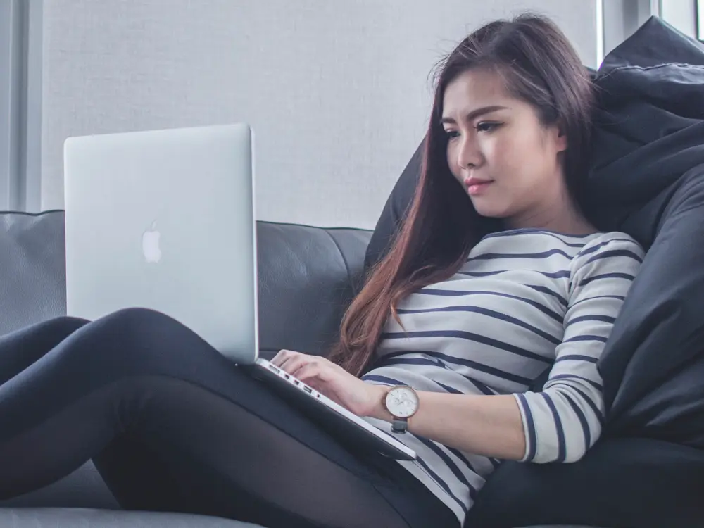 A woman relaxing at home, typing on her laptop
